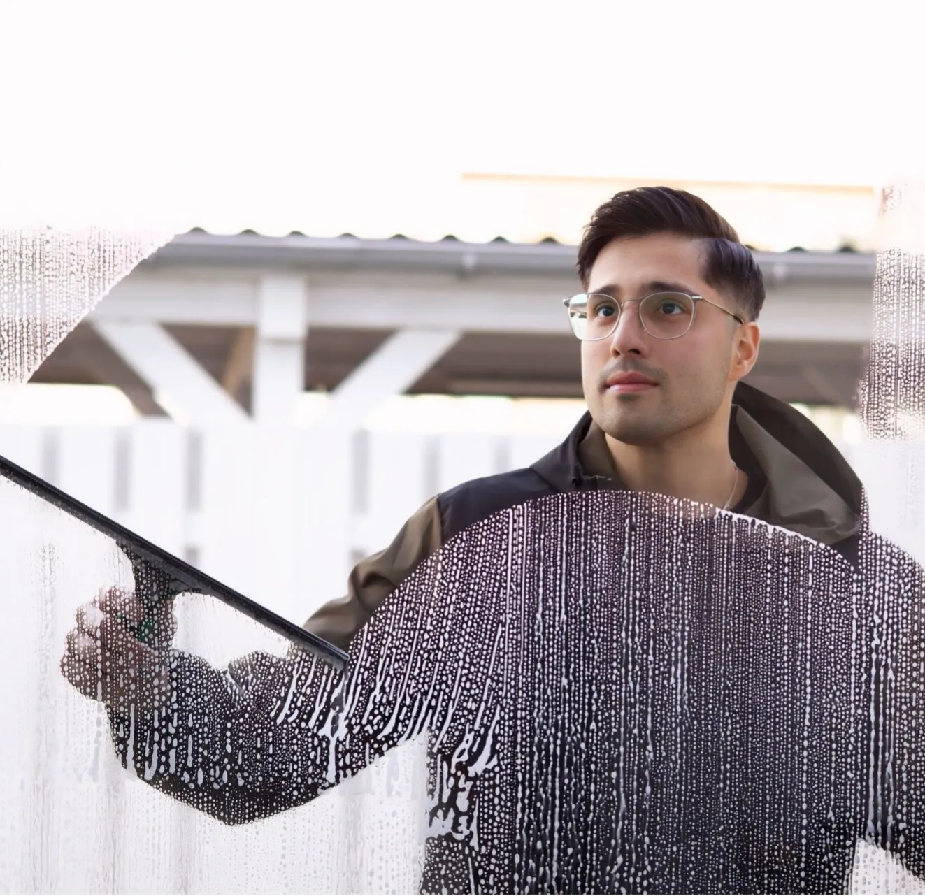 Ahmad Atayi zieht Schaum von einer Glasscheibe ab – dahinter wird er klar sichtbar
